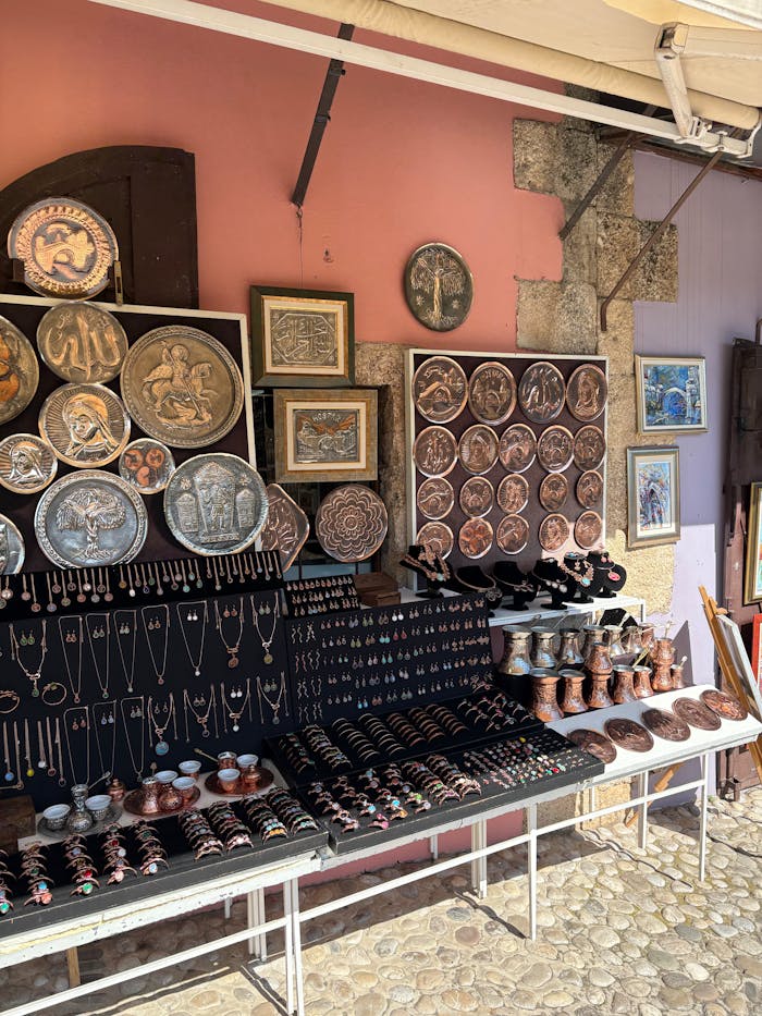Handmade copper artwork and jewelry displayed in an outdoor market stall, showcasing craftsmanship.